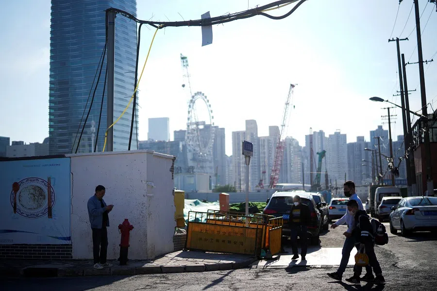 People cross an unfinished road in Shanghai, China, 10 October 2022. (Aly Song/Reuters)