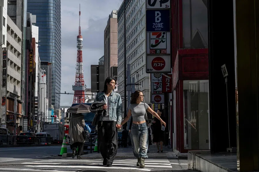 People cross a street as the Tokyo Tower looms in the background in Tokyo, Japan, on 10 October 2024. (Yuichi Yamazaki/AFP)