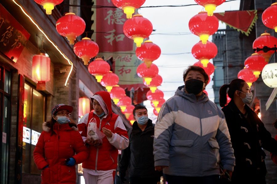 People walk in a historic street decorated for Lunar New Year celebrations in Beijing, China, 8 February 2021. (Thomas Peter/Reuters)
