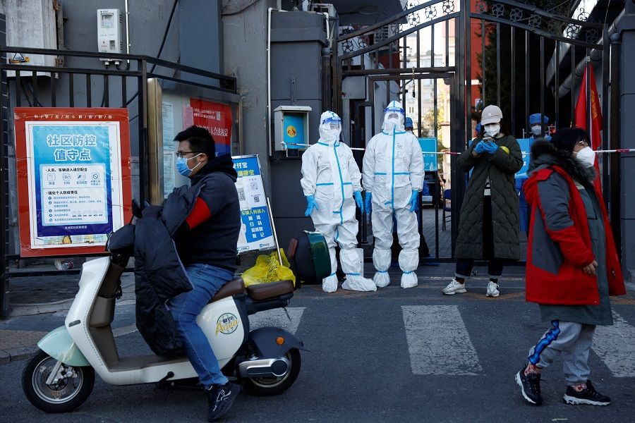 Security personnel in protective suits stand at the gate of a residential compound that is under lockdown as outbreaks of Covid-19 continue in Beijing, China, 22 October 2022. (Thomas Peter/Reuters)