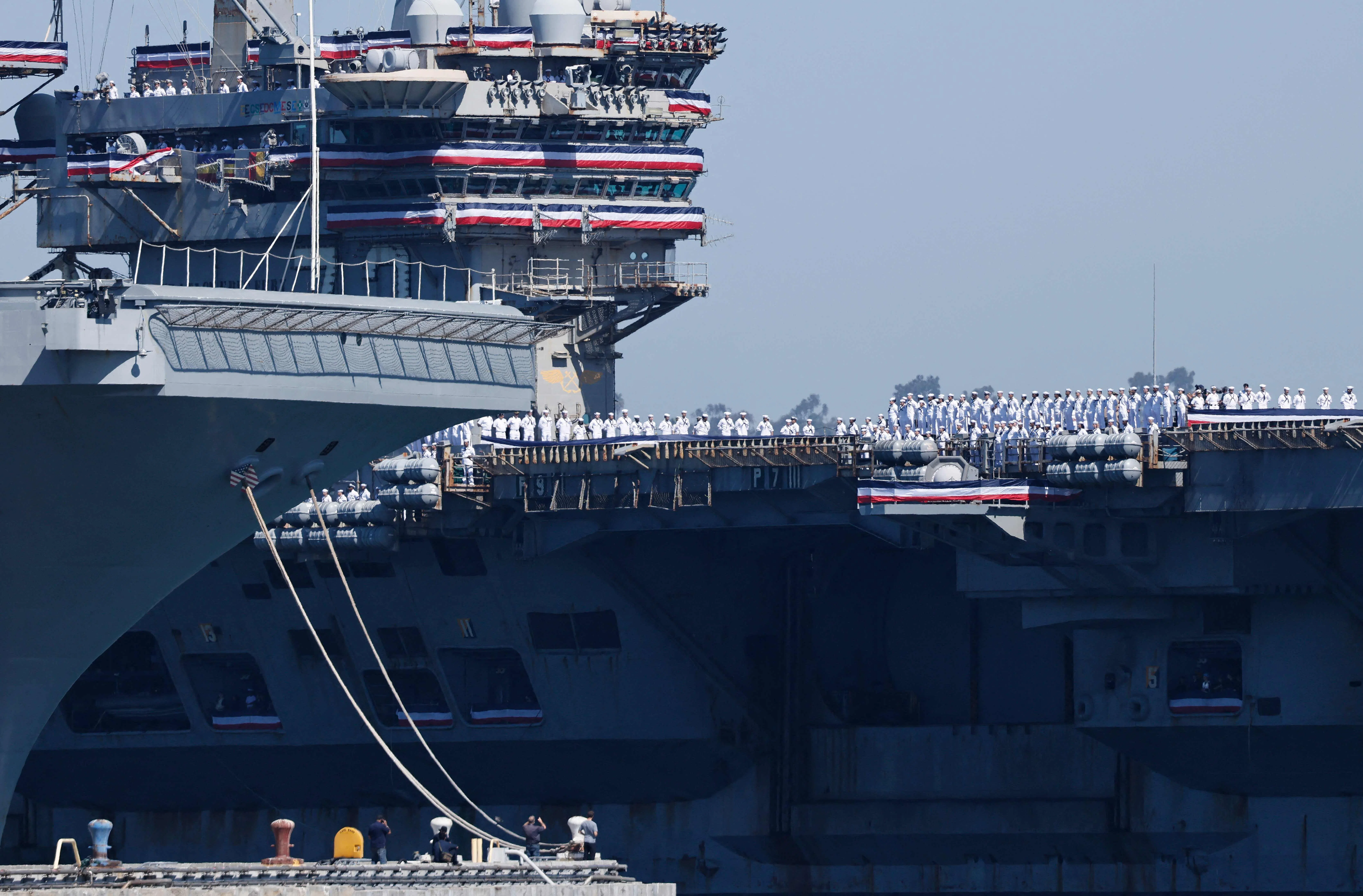Sailors aboard the USS Abraham Lincoln Nimitz-class aircraft carrier look on as the ship docks at its homeport at Naval Air Station North Island on return from a historic 10-month deployment on 8 October 2026 in Coronado, California.