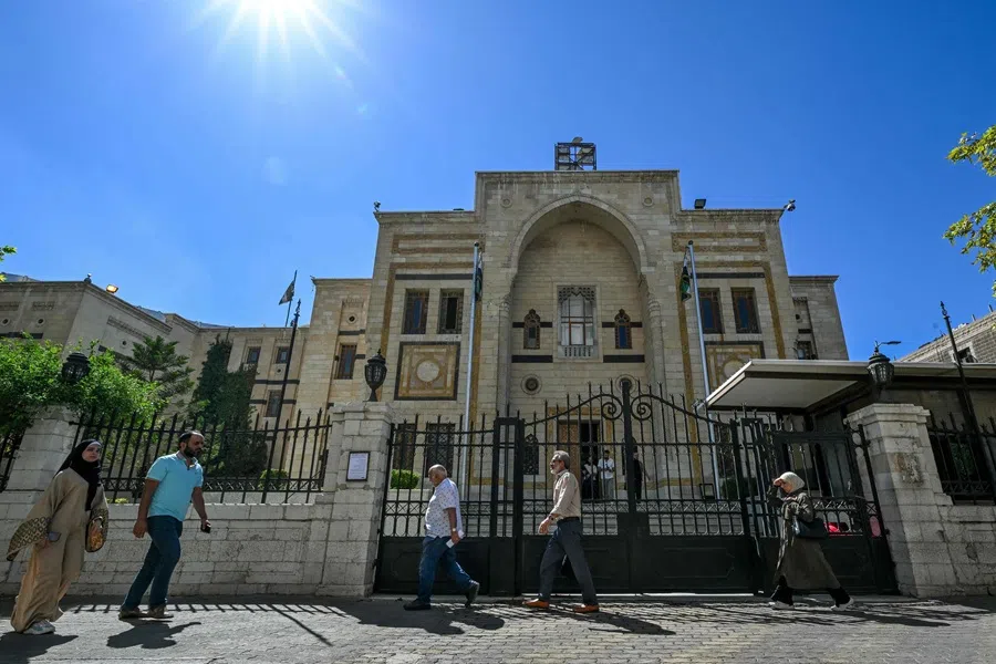 People walk past the parliament building in Damascus on 1 October 2025. (Louai Beshara/AFP)