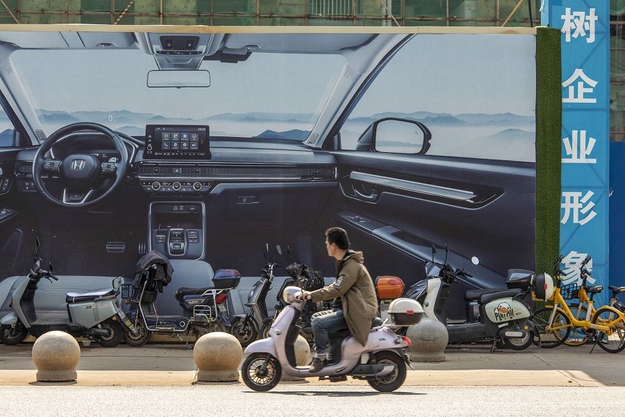 A motorcyclist passes an advertisement for electric vehicle at the Car Valley area in Wuhan, China, on 24 October 2023. (Bloomberg)