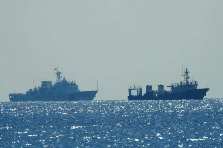 A Chinese Coast Guard patrol ship (left) is seen near an unidentified vessel at Whitsun Reef, South China Sea, in a handout photo distributed by the Philippine Coast Guard, 15 April 2021. (Philippine Coast Guard/Handout via Reuters)