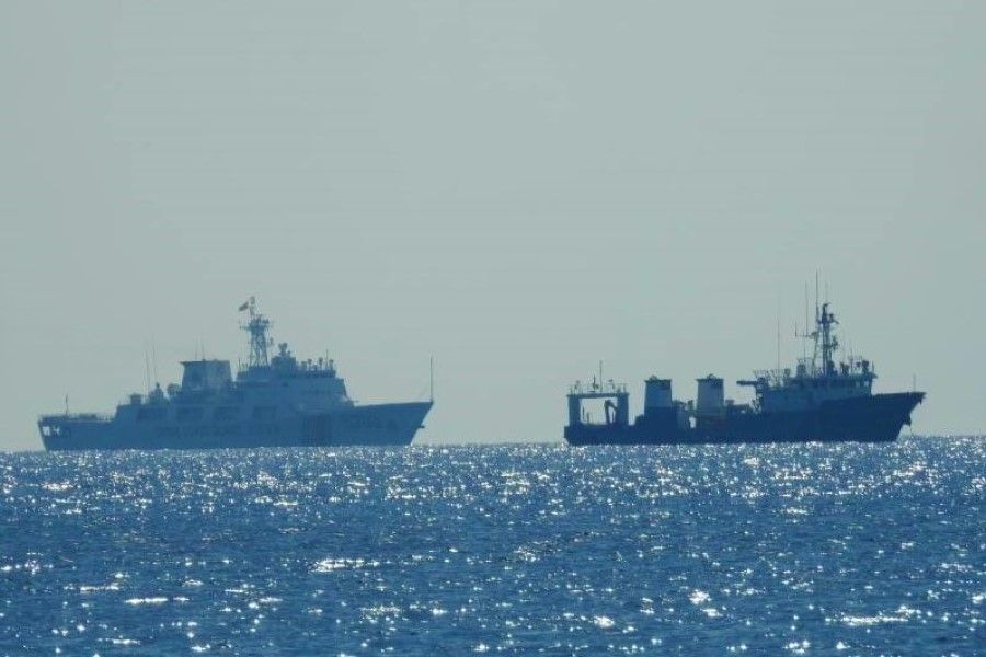 A Chinese Coast Guard patrol ship (left) is seen near an unidentified vessel at Whitsun Reef, South China Sea, in a handout photo distributed by the Philippine Coast Guard, 15 April 2021. (Philippine Coast Guard/Handout via Reuters)