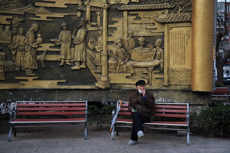 A man lowers his mask to smoke a cigarette in Beijing on 9 March 2020. (Greg Baker/AFP)