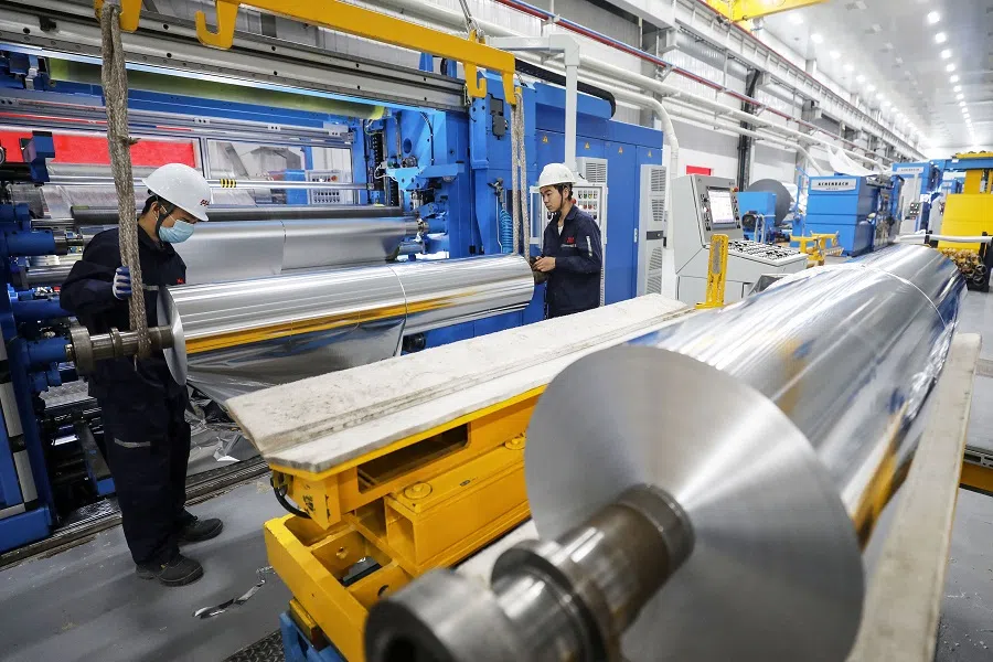 This photo taken on 17 October 2021 shows a worker checking rolls of sheet aluminium at a factory in Huaibei, Anhui province, China. (STR/AFP)