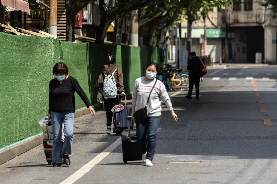 Residents pulling luggage pass barriers in a neighbourhood during a lockdown due to Covid-19 in Shanghai, China, on 3 May 2022. (Bloomberg)