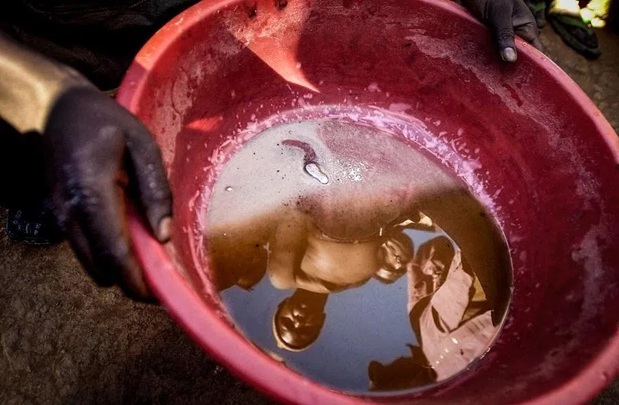 A picture taken 26 May 2006 in Iga Barriere, in the Ituri region of the Democratic Republic of the Congo, shows Congolees miners reflecting in a pan containing mercury, used to separate gold from the dirt, at a gold field on the banks of the Iga river.