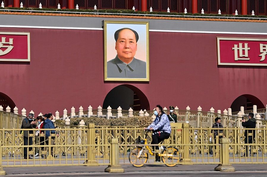People are seen next to a portrait of late communist leader Mao Zedong on Tiananmen Gate in Beijing, China, on 3 March 2022. (Hector Retamal/AFP)