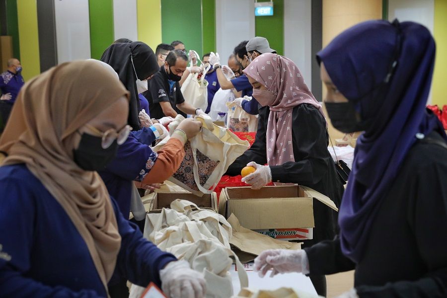 Volunteers packing specially designed patchwork-themed care bags for distribution to food delivery workers and neighbourhood cleaners on 23 January 2022. This distribution drive is a collaboration between the People's Association Malay Activity Executive Committees Council (PA MESRA) and Tampines Central Community Club's Malay Activity Executive Committee (MAEC). (SPH Media)
