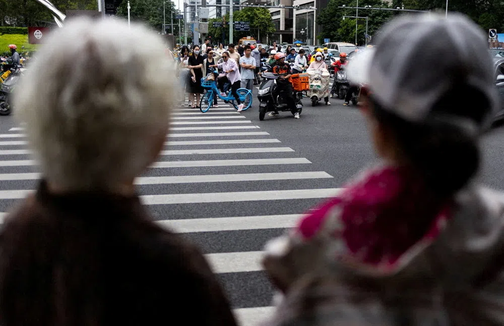 Elderly women look at people waiting to cross the street in Beijing, China, on 26 June 2026.