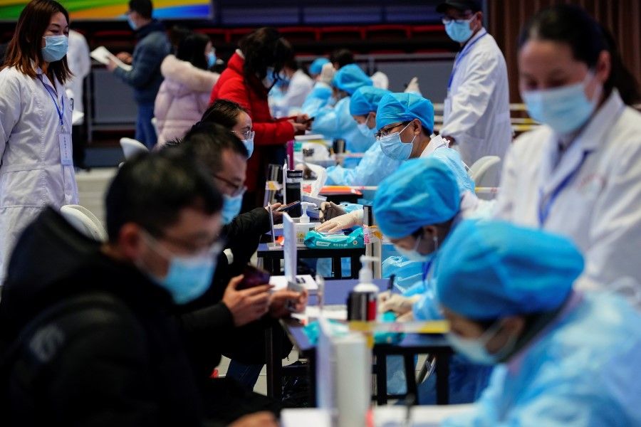 People fill forms before receiving a dose of a coronavirus disease (COVID-19) vaccine at a vaccination site, during a government-organised visit, following the coronavirus disease (COVID-19) outbreak, in Shanghai, China, 19 January 2021. (Aly Song/Reuters)