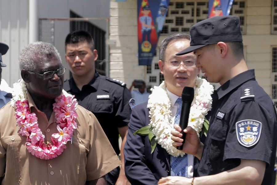 Solomon Islands Prime Minister Manasseh Sogavare (left) looks on with Li Ming (second from right), China's ambassador to the Solomon Islands, as they listen to a Chinese police officer (right) during a ceremony in Honiara, Solomon Islands, on 4 November 2022. (Gina Maka/AFP)
