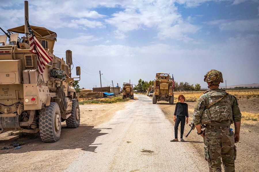 A US soldier stands near a child during a patrol near the Syrian-Turkish border in one of the villages that was subject to bombardment the previous week in the countryside east of Qamishli in Syria's northeastern Hasakah province on 21 August 2022. (Delil Souleiman/AFP)