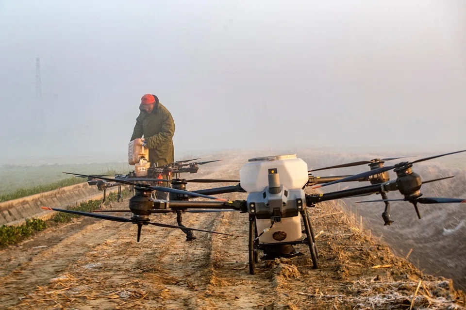 A farmer fills pesticide in a drone before spraying a wheat field in Taizhou, Jiangsu province, China, on 28 February 2023. (AFP)