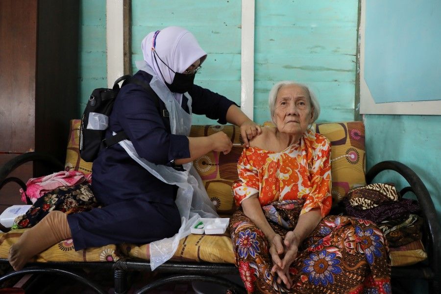 A woman gets a shot of Sinovac coronavirus disease (Covid-19) vaccine at home, administered by a healthcare worker in Sabak Bernam, Malaysia, 1 July 2021. (Lim Huey Teng/Reuters)