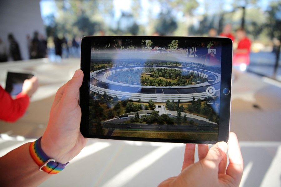 An Apple employee uses an iPad with an augmented reality app on it to show off features of the new Apple Park at the Apple Visitor Center in Cupertino, California, 17 November 2017. (Elijah Nouvelage/Reuters)