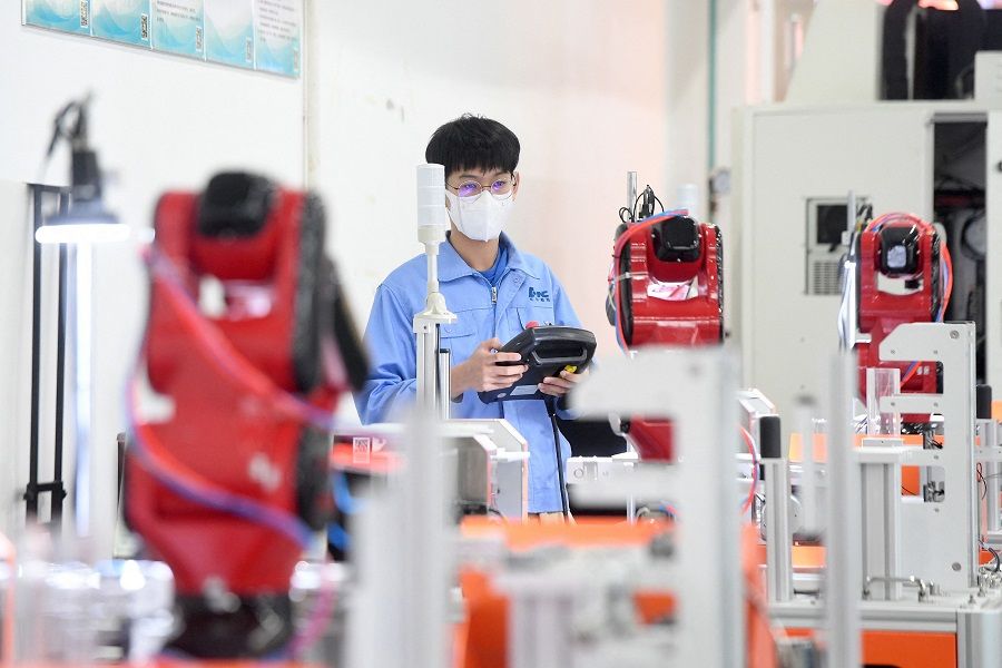This photo taken on 13 April 2022 shows a worker producing industrial robots at a factory in Wuhan, Hubei province, China. (AFP)