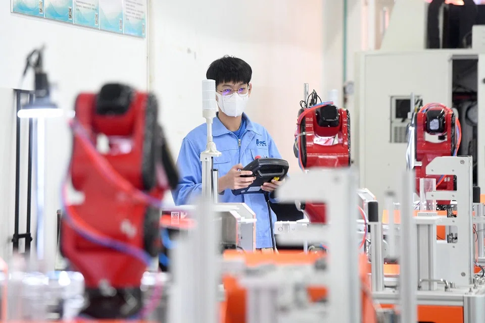 This photo taken on 13 April 2022 shows a worker producing industrial robots at a factory in Wuhan, Hubei province, China. (AFP)