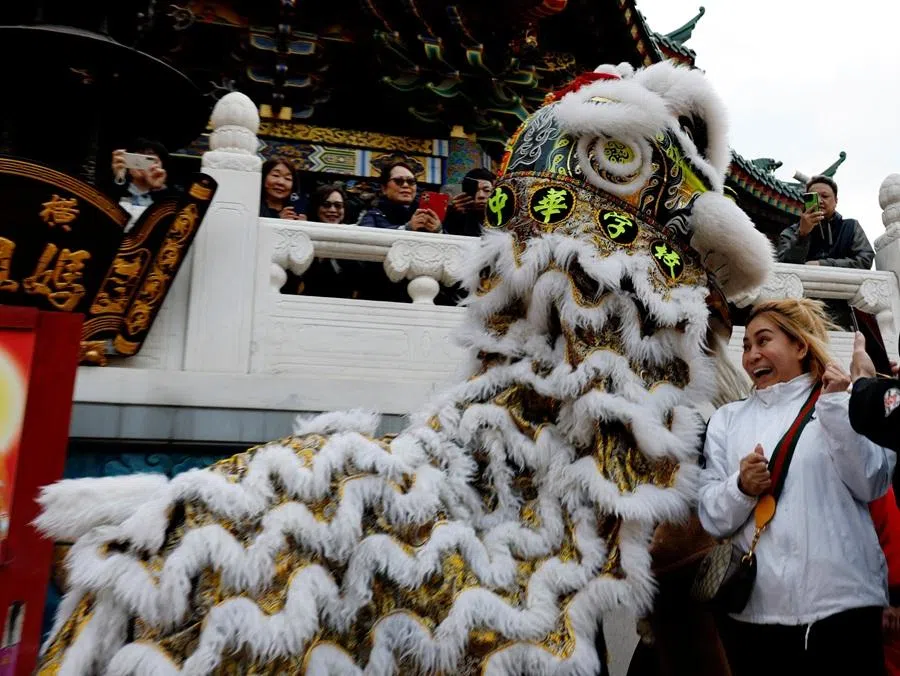 A woman reacts as performers acting as a lion playfully bite the heads of onlookers to bestow good fortune at a temple during a lion dance as part of Lunar New Year celebrations in Chinatown in Yokohama, Japan, on 17 February 2026. (Kim Kyung-Hoon/Reuters)