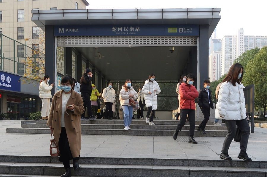 People walk out of a subway station during morning rush hour in Wuchang district, in Wuhan, Hubei province, China, 9 December 2022. (Martin Pollard/Reuters)