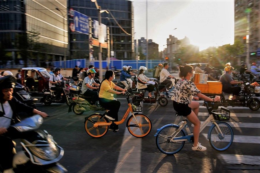 People ride bicycles and motorbikes on a street, in Shanghai, China, 31 May 2021. (Aly Song/Reuters)