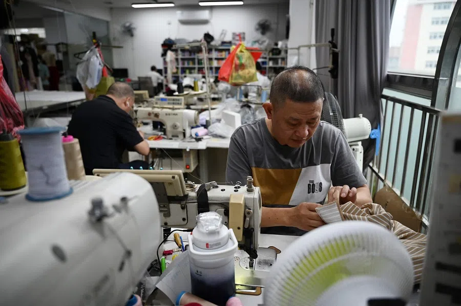 This photo taken on 14 November 2024 shows workers sewing clothing at a workshop in Guangzhou, in China’s southern Guangdong province. (Greg Baker/AFP)