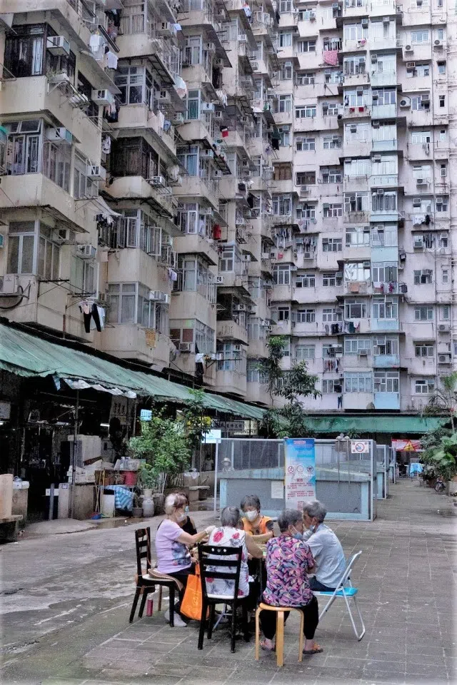 People play card games in an open area of a residential building in Hong Kong on 21 August 2021. (Bertha Wang/AFP)