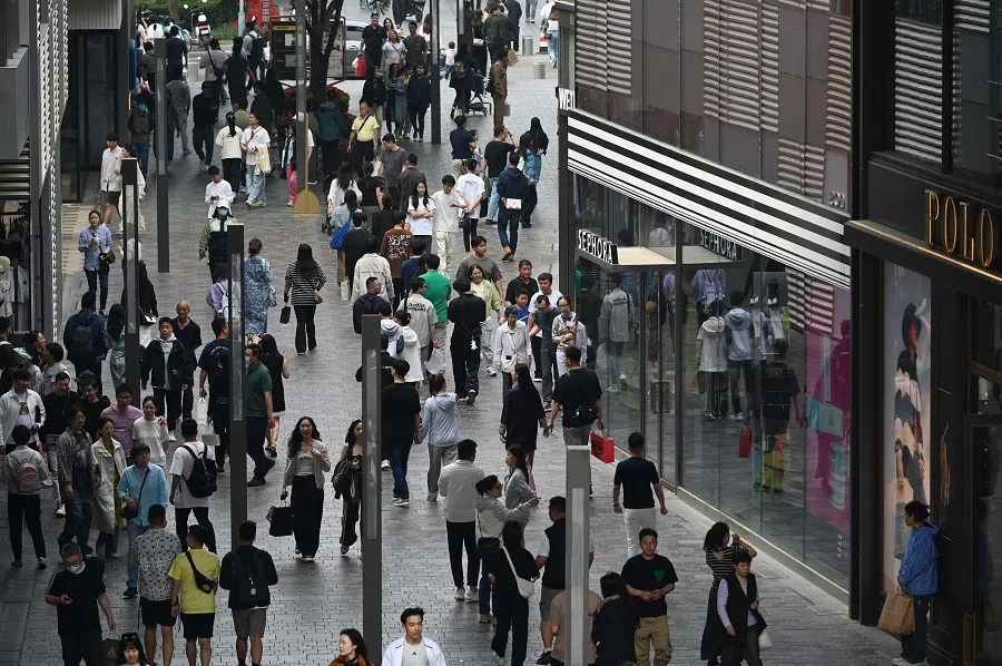 People walk through a shopping mall in Beijing, China on 5 May 2024. (Greg Baker/AFP)