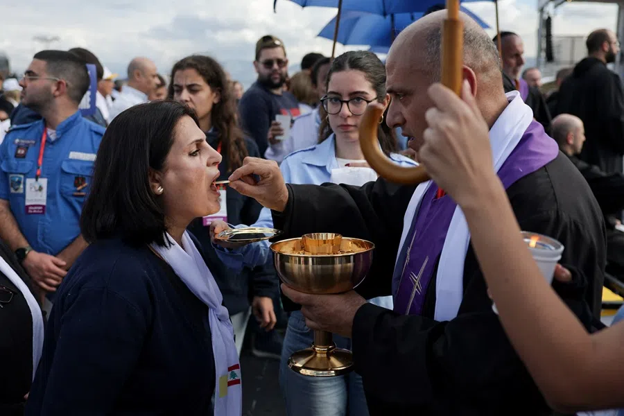 A woman receives Holy Communion as she attends the Holy Mass at the Waterfront, during Pope Leo XIV's first apostolic journey, in Beirut, Lebanon, 2 December 2025. (Khalil Ashawi/Reuters)