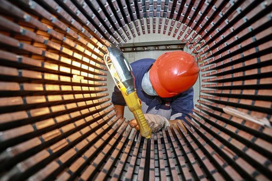 A worker checks a rotor core used for wind turbines at a factory in Nantong, Jiangsu province, China, on 20 September 2023. (AFP)