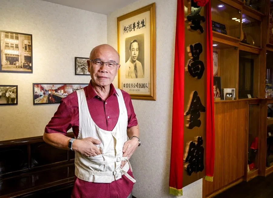 Ho Nai Chuen wears the vest that his mother had sewn specially design to hold gold bars. Behind him is a portrait of Ho’s father and founder of On Cheong, Ho Yew Ping. (Jonathan Yeap/SPH Media)