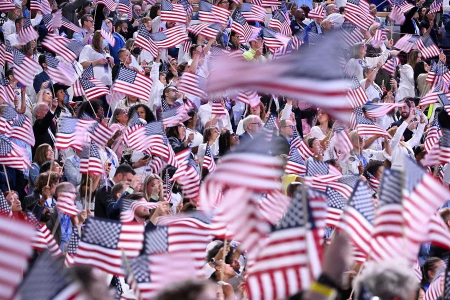Attendees wave US flags during the Democratic National Convention (DNC) at the United Center in Chicago, Illinois, on 22 August 2024.