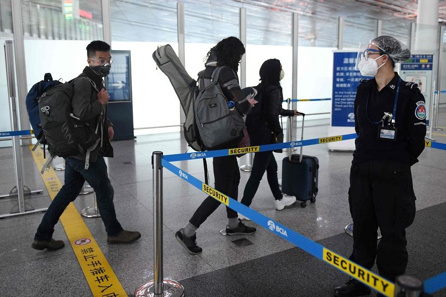 Wall Street Journal reporters Stu Woo (left), Julie Wernau (centre) and Stephanie Yang head into the security area at Beijing Capital Airport on 28 March 2020 after being forced to leave China. (Greg Baker/AFP)