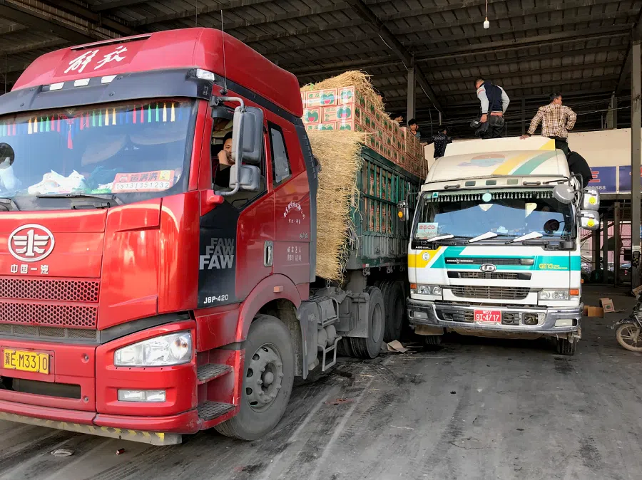 Myanmar workers load boxes of watermelons from a Myanmar truck to a Chinese truck, Ruili, Yunnan province, on 4 January 2019. (Chen Xiangming)