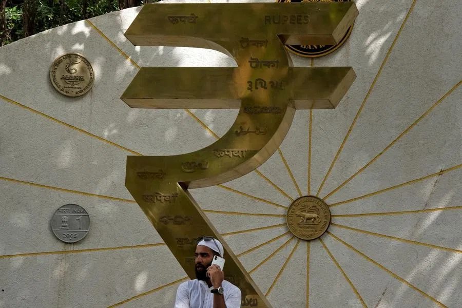 A man speaks on his mobile phone next to an installation of the Rupee logo and Indian currency coins outside the Reserve Bank of India (RBI) headquarters in Mumbai, India, on 1 August 2025.