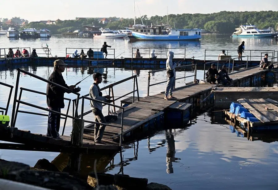 People fish at a pier near Denpasar on Indonesia's resort island of Bali on 12 April 2026. (Sonny Tumbelaka/AFP)