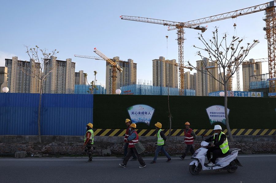 Workers walk past a construction site near residential buildings in Beijing, China, 14 April 2022. (Tingshu Wang/File Photo/Reuters)