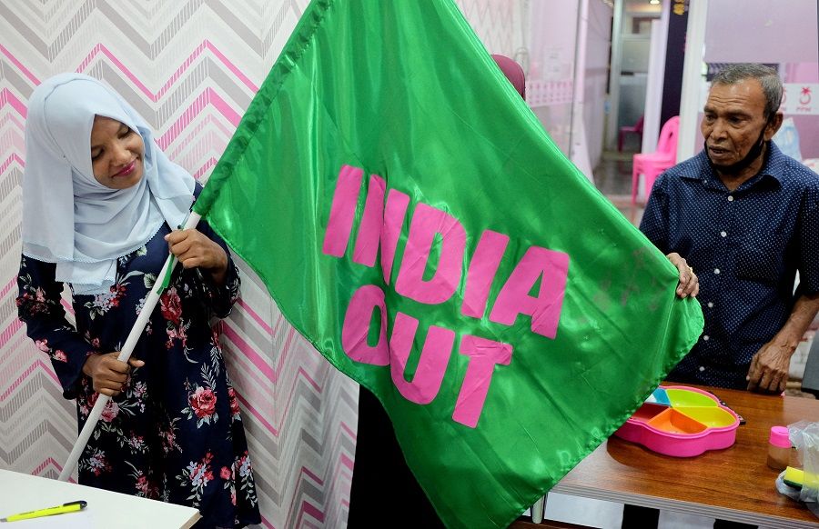 A Progressive Party of Maldives worker poses with an "India Out" flag in Male, Maldives, on 21 March 2022. (Alasdair Pal/Reuters)
