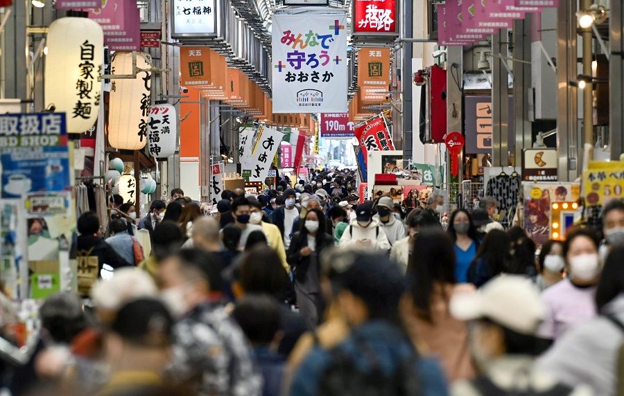 Pedestrians wearing protective face masks are seen at a shopping district in Osaka, Japan, in this photo taken by Kyodo, 7 April 2021. (Kyodo via Reuters)