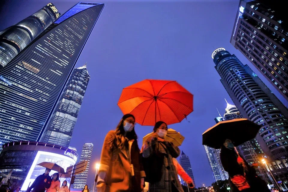 People walk with umbrellas in Lujiazui financial district in Pudong, Shanghai, on the day of the opening session of the National People's Congress (NPC), China, 5 March 2021. (Aly Song/Reuters)
