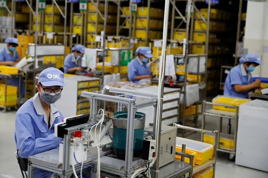 Employees wearing face masks work at a factory of the component maker SMC in Beijing, China on 13 May 2020. (Thomas Peter/Reuters)