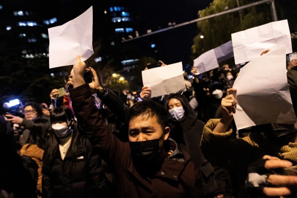 People hold white sheets of paper in protest over coronavirus disease (Covid-19) restrictions, after a vigil for the victims of a fire in Urumqi, as outbreaks of COVID-19 continue, in Beijing, China, 28 November 2022. (Thomas Peter/Reuters)