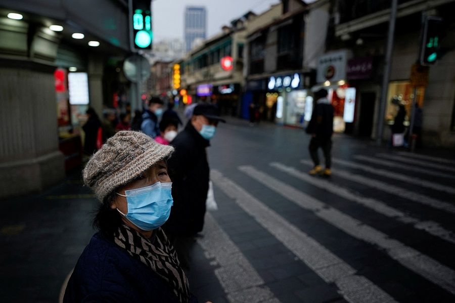 People wearing protective masks walk on a street in Shanghai, China, 4 January 2022. (Aly Song/Reuters)