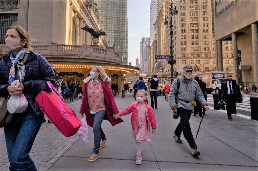 A family wearing face masks walk on a street in New York, US, on 6 December 2021. (Ed Jones/AFP)