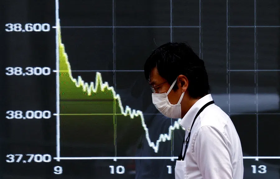 A person walks past an electronic screen displaying the graph showing today’s movements of Japan’s Nikkei share average outside a brokerage in Tokyo, Japan, on 1 August 2024. (Issei Kato/Reuters)