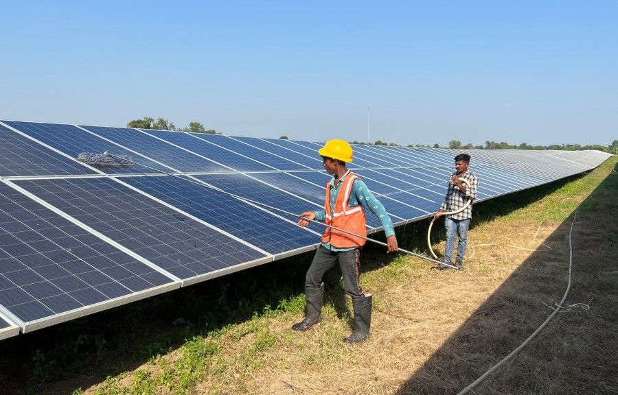 Workers clean panels at a solar park in Modhera, India's first round-the-clock solar-powered village, in the western state of Gujarat, India, 19 October 2022. (Sunil Kataria/Reuters)