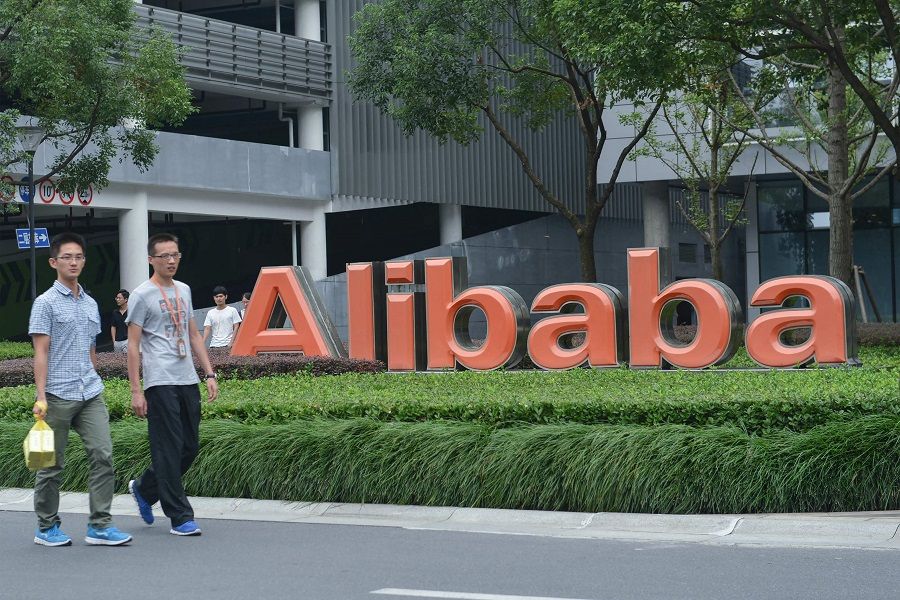 Staff members walk past a logo of Chinese e-commerce giant Alibaba at its headquarters in Hangzhou, Zhejiang province, China, on 27 May 2022. (AFP)