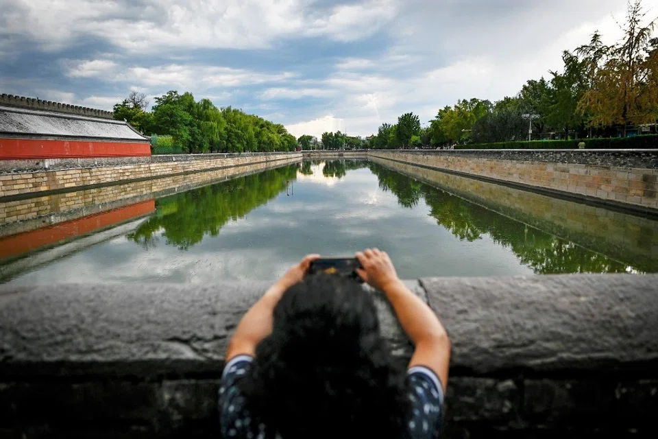 A woman uses her mobile phone to take pictures at the Forbidden City in Beijing on 1 September 2020. (Wang Zhao/AFP)